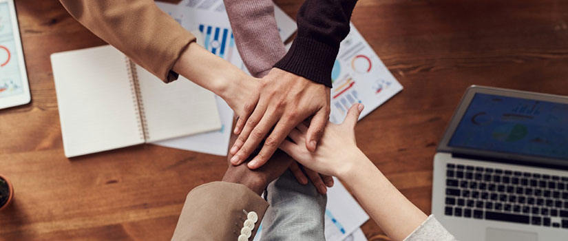 Hands of varying skin tones overlap in a circle. 