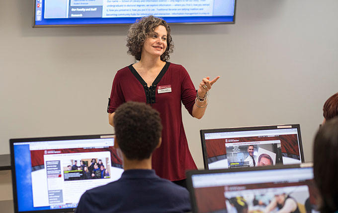 Professor addresses students from the front of the classroom.