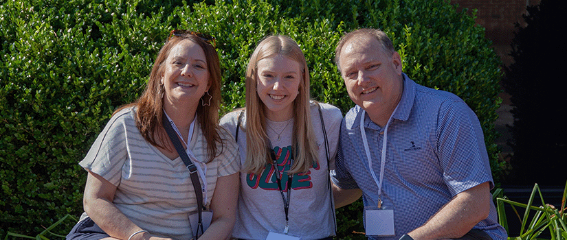 A student and their family members posing for a photo outside of the Russell House