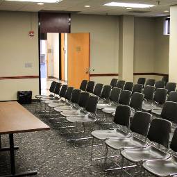 rows of chairs in a classroom with desk and a door leading out