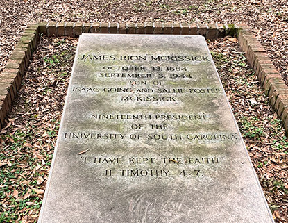 Stone grave marker of John R. McKissick surrounded by brick and leaves. 