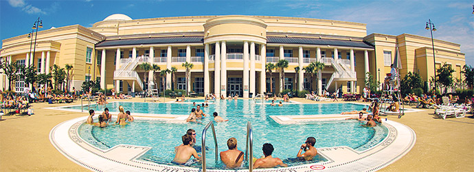 Students sitting around the outdoor pool at the fitness center on a beautiful sunny day. 