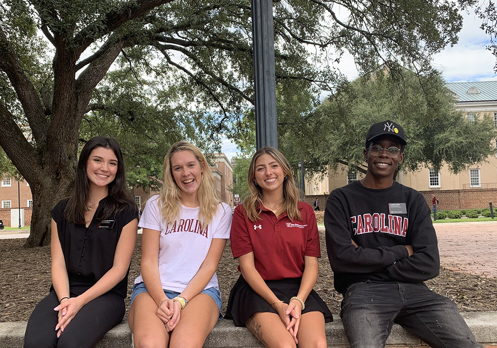 four students workers sit together on a brick wall