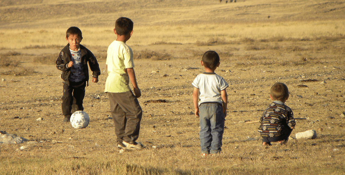 Young children play with a soccer ball in an open field in the village of Koyan, Kazakhstan. Photo by Magdalena Stawkowski.