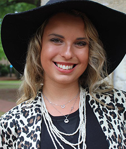 woman smiling with a outside with a black hat on