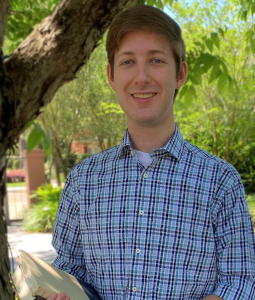 Headshot of Andrew Cerise standing outside wearing a blue plaid shirt.