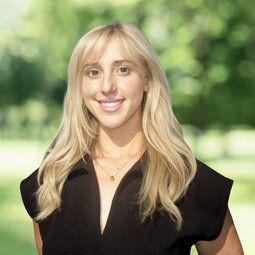 Headshot of a blond graduate smiling while standing outdoors