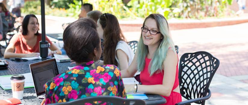 Woman sitting among other students outside, laughing