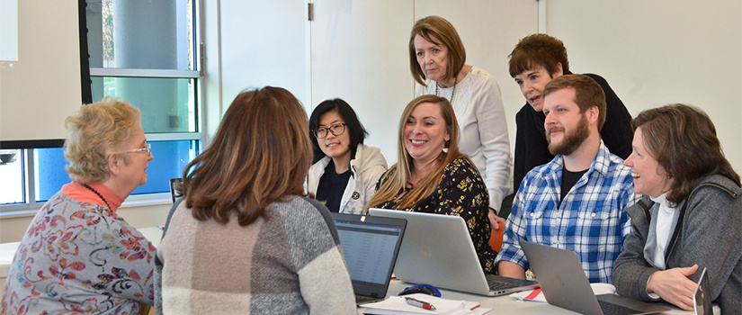  a diverse group of people gathered around REM Center faculty member Ashlee Lewis, Ph.D.