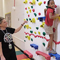 Susan Heid instructing child on adaptive climbing wall