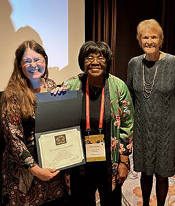 Catherine Compton-Lilly holding her  award with two oter women.