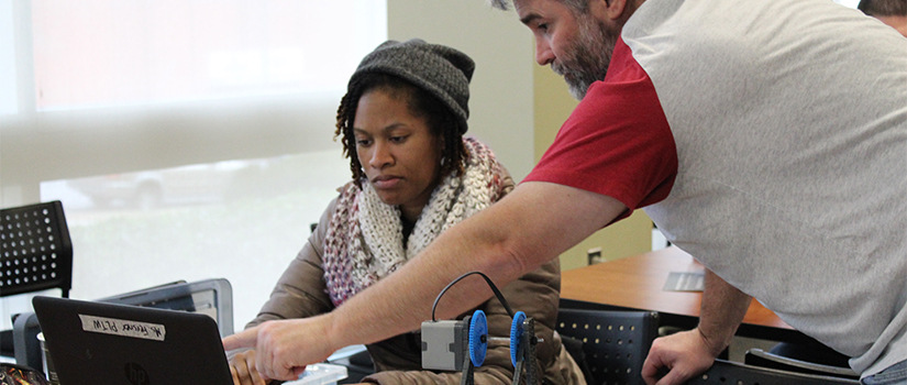 two teachers work on a laptop