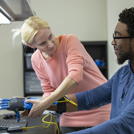 a woman helps a man fit a prosthetic arm