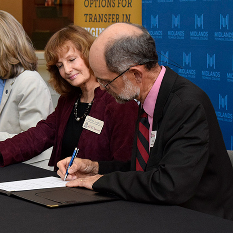 Jed Lyons signs document at news conference