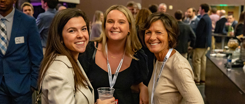 Two students pose for a photo with senior instructor Susan O'Malley at the Sport Entertainment and Venues Tomorrow conference.