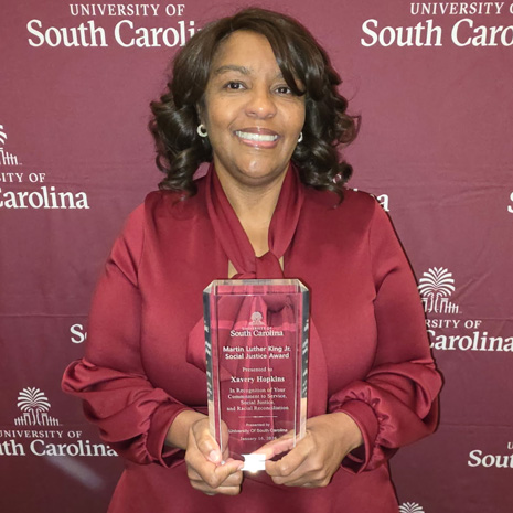 Xavery Hopkins holds her award while standing in front of the USC step-and-repeat backdrop