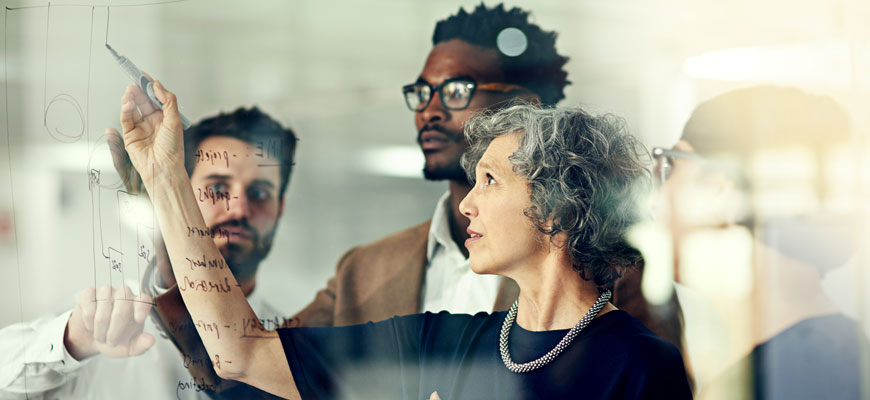 Group of people writing ideas on a window inside of an office