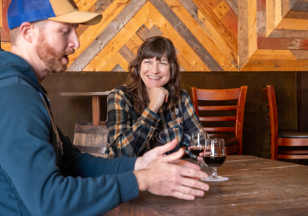 two people sit at a table with drinking glasses