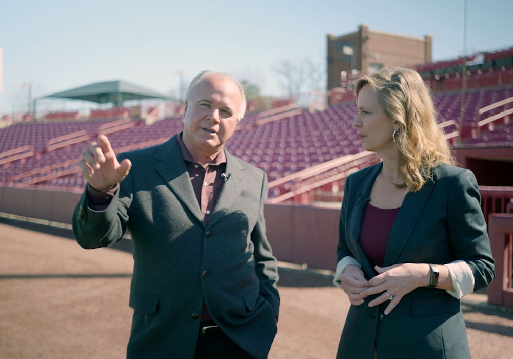 two people stand in a baseball stadium