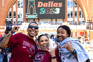 Three fans wearing Gamecock gear hold up spurs up signs in Dallas for the Final Four NCAA Tournament game.