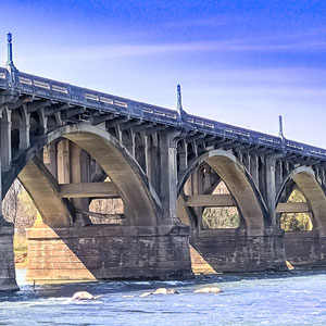 photo of a bridge over a river with blue sky in the background