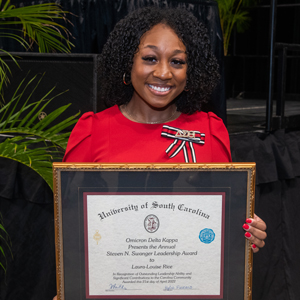 Laura-Louise Rice holds a framed copy of the Steven N. Swanger award