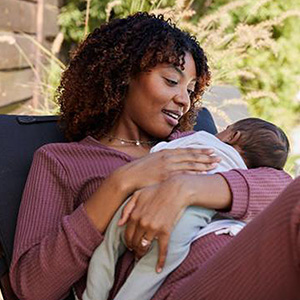 Black woman with curly hair holding infant 