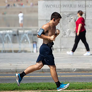 A young male jogs for exercise outdoors on a hot day.