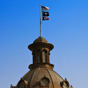 american flag, palmetto flag and USC flag flying above dome on statehouse