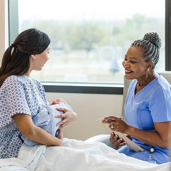 A mother holds her infant while consulting a nurse midwife. 