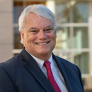 Man in a suit standing in front of a campus building