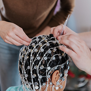 Hands position an EEG net on a person's head.