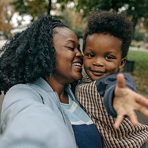 A mother smiles while holding a toddler.