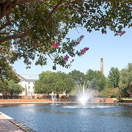 Brown smokestack sits behind fountain spraying water up