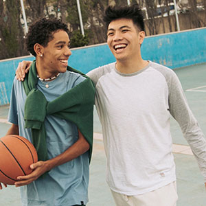 Two teenage boys smiling on a basketball court in a candid photo 