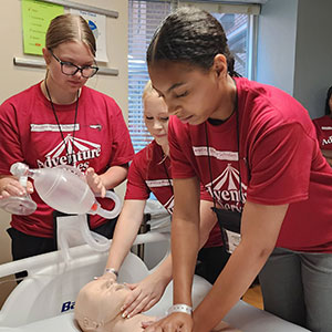 Young woman performing CPR on a training manikin 