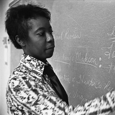 A historic photo of Edna Smith Primus writing on a blackboard. 